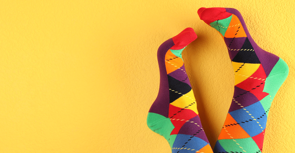 someone wearing colorful socks kicks their feet up on a yellow wall