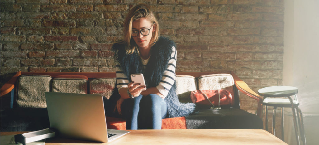 blond woman checking phone and using computer