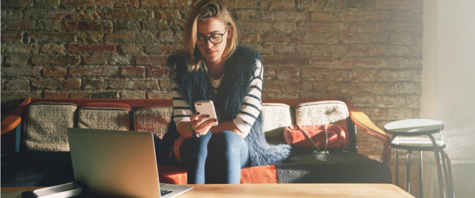 blond woman checking phone and using computer