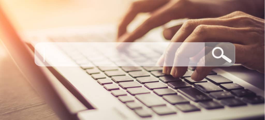 Image of hands typing on keyboard with search bar overlay