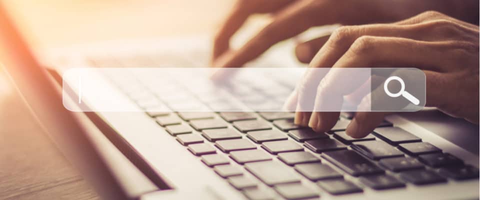 Image of hands typing on keyboard with search bar overlay