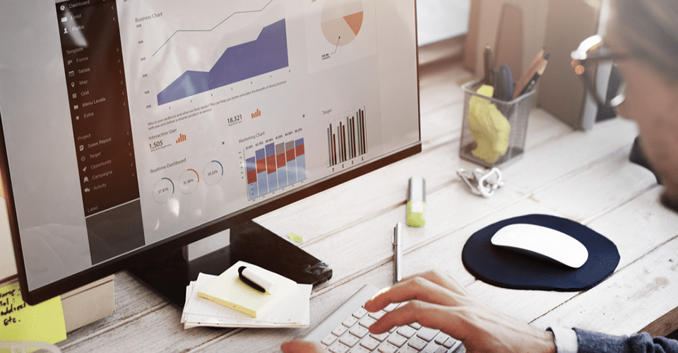 a man looks at an analytics dashboard on a desktop computer