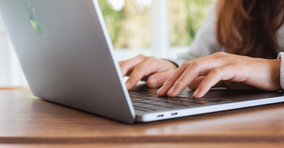 A woman using and typing on Apple MacBook Pro laptop computer