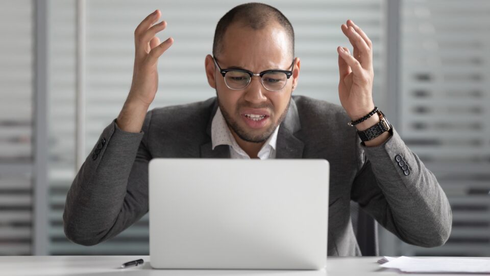Angry stressed african business man using laptop mad about broken computer online problem annoyed with slow stuck laptop error, crazy about system virus or data loss, outraged with website mistake